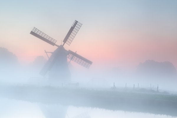 Windmühle am Fluss mit Nebelschwaden im Morgenlicht