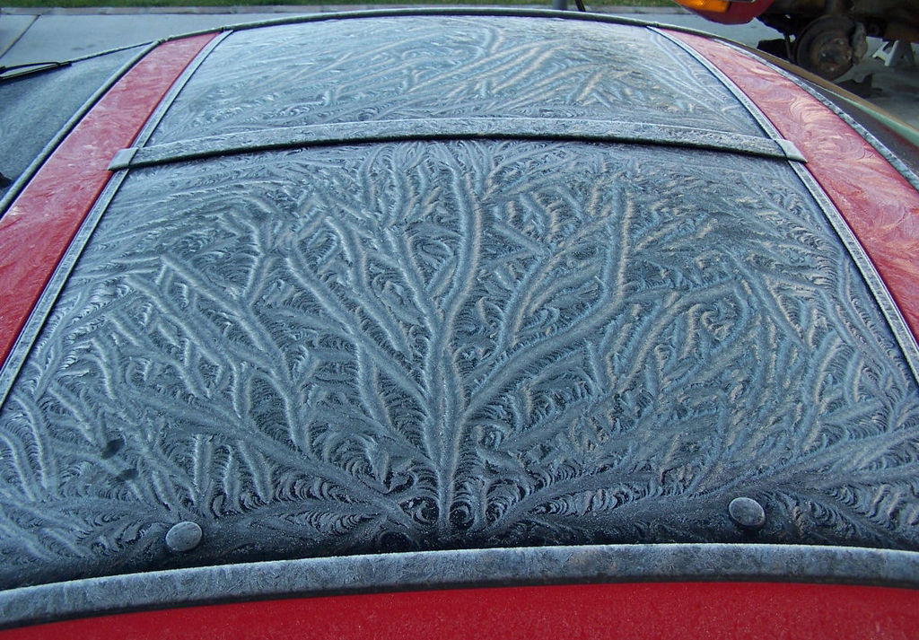 Frost auf dem Oberlicht eines parkierten roten Autos