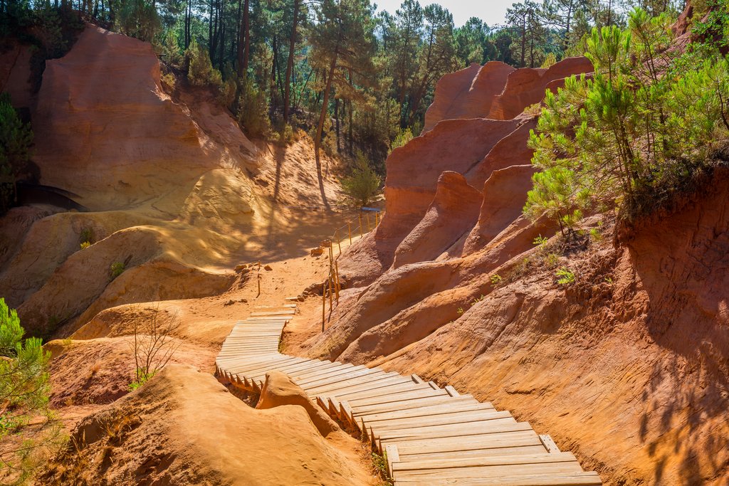 Holzbohlenpfad durch eine Landschaft mit intensiv orangefarbener Erde