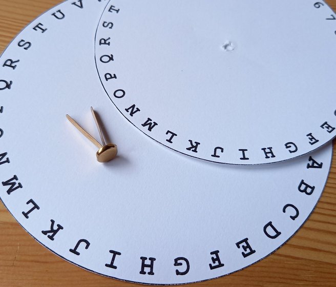 Deux cercles en papier de taille différente avec une bordure de chiffres et de lettres, attache parisienne