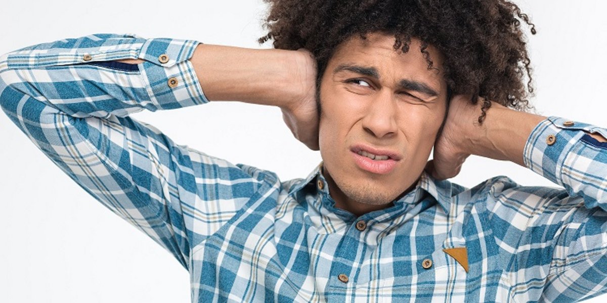 Un homme se bouchant les oreilles à cause du bruit