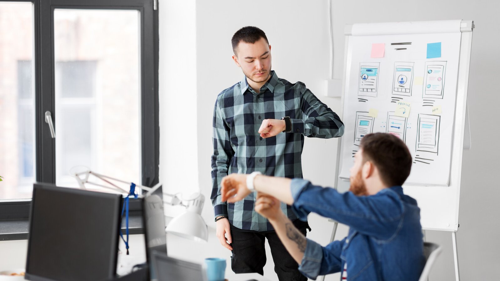 Mann zeigt seinem Arbeitskollegen eine Smartwatch