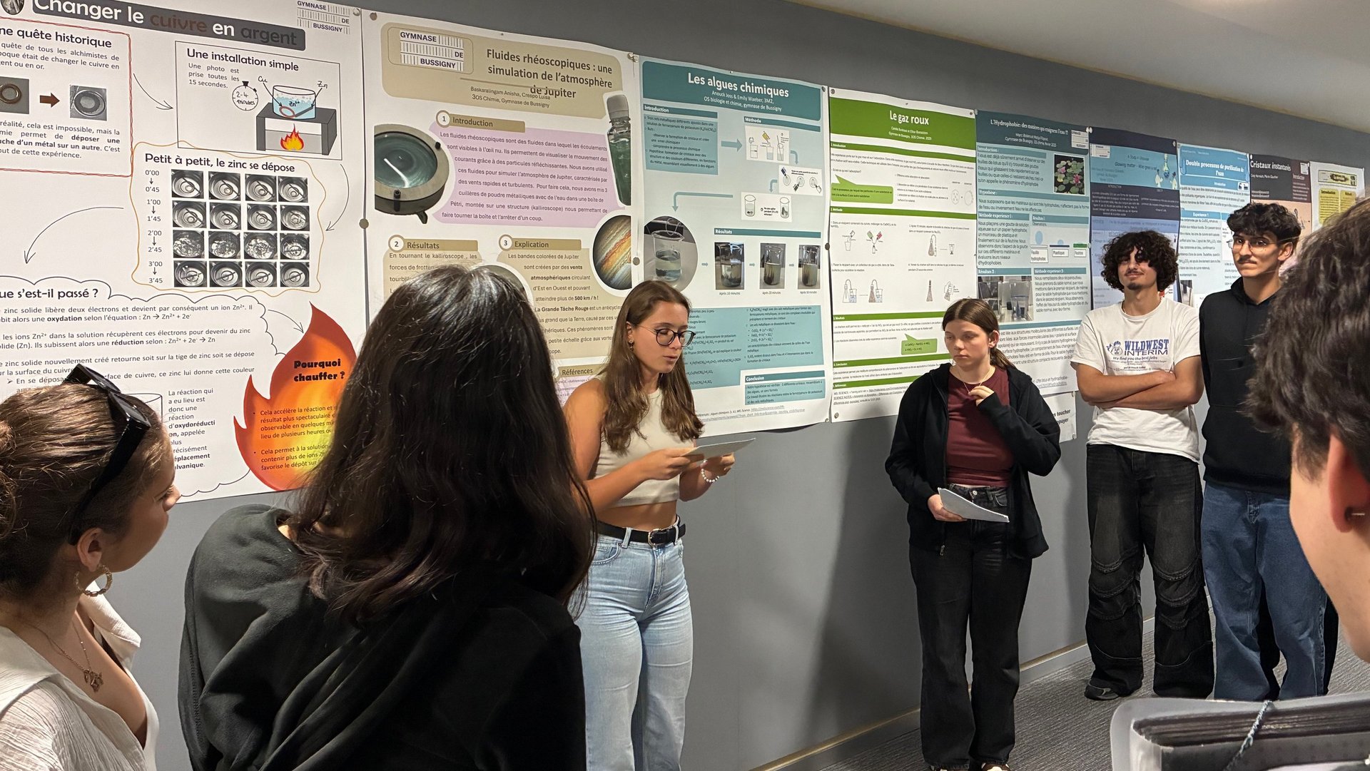 Elèves du gymnase présentant leur poster à d'autres élèves et enseignants