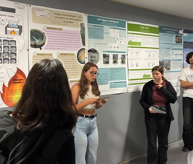 Elèves du gymnase présentant leur poster à d'autres élèves et enseignants