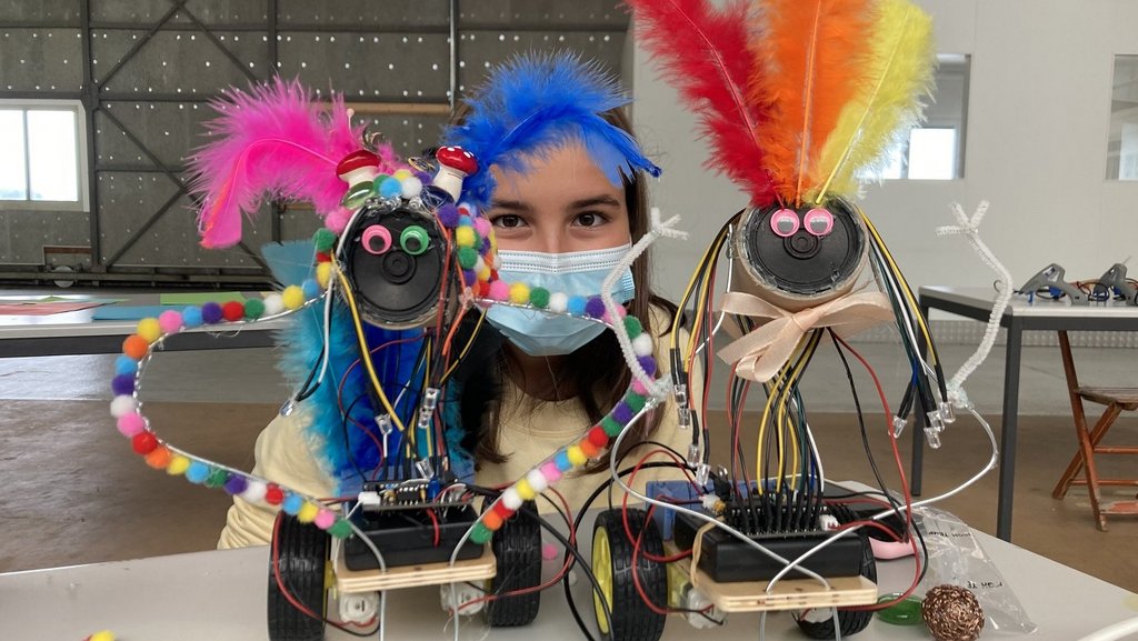 Mädchen mit bunten, selbst konstruierten fahrenden Robotertieren