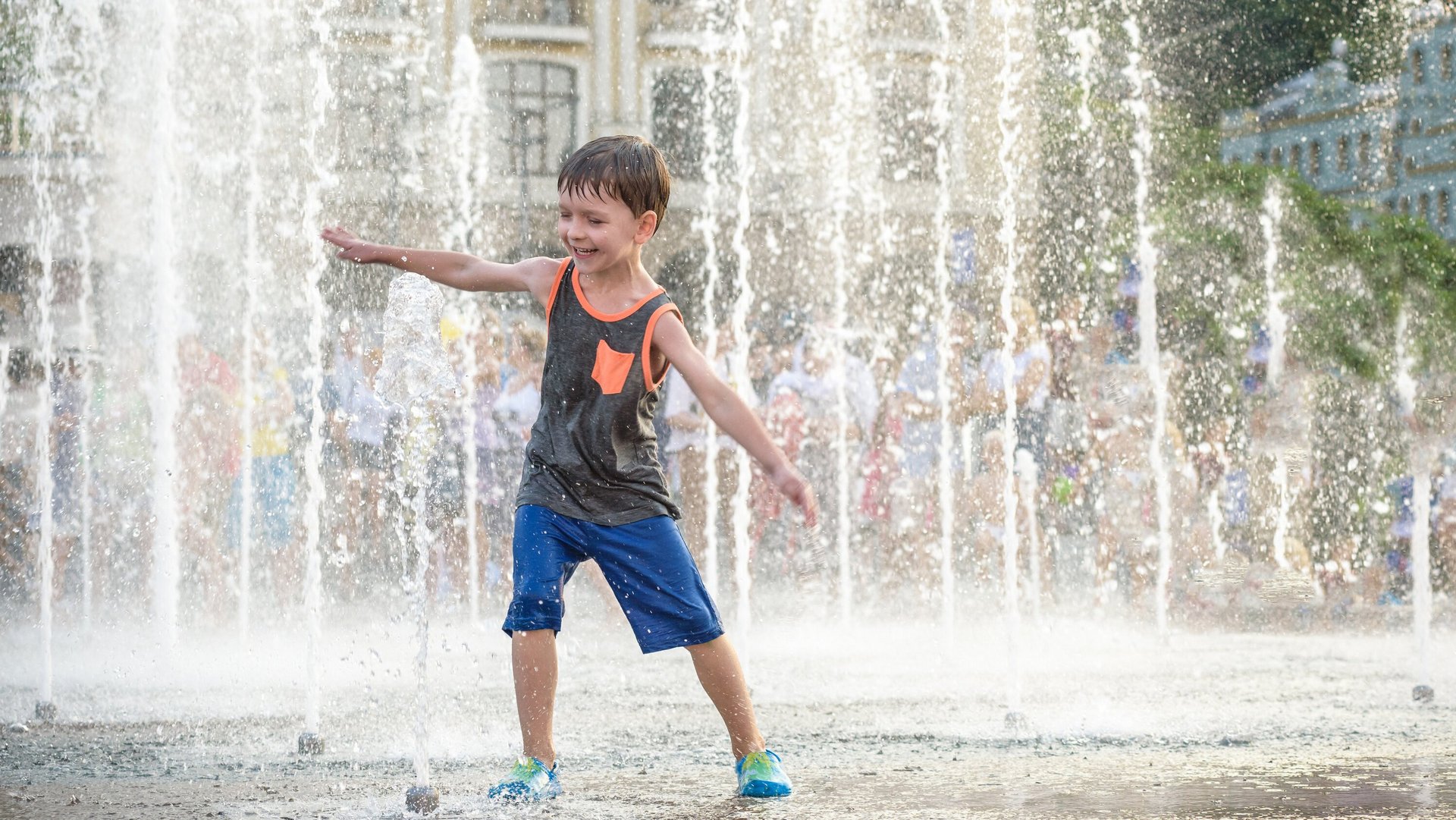 Ein Kind spielt mit dem Wasser eines Springbrunnens