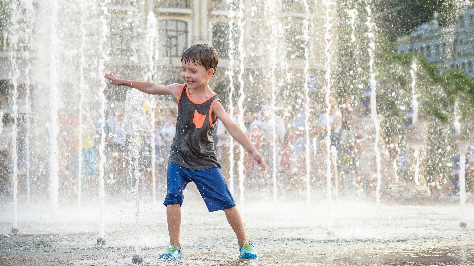 un enfant joue avec l'eau d'une fontaine 