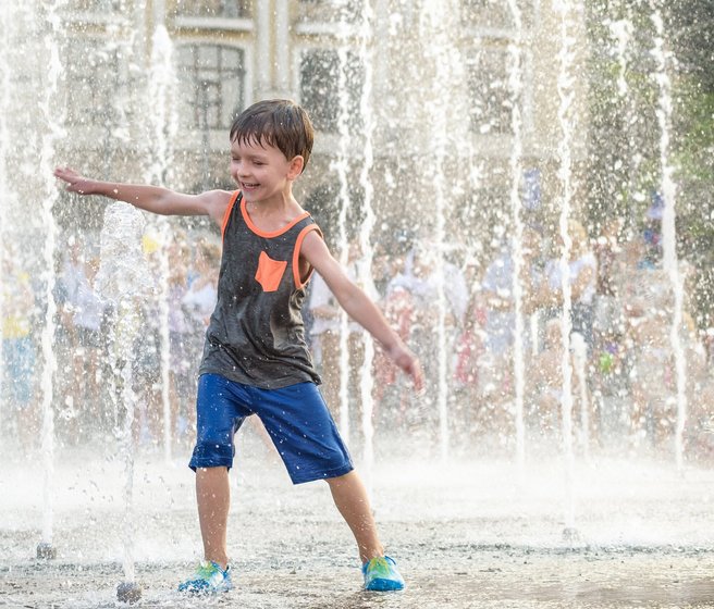 un enfant qui joue avec l'eau d'une fontaine 