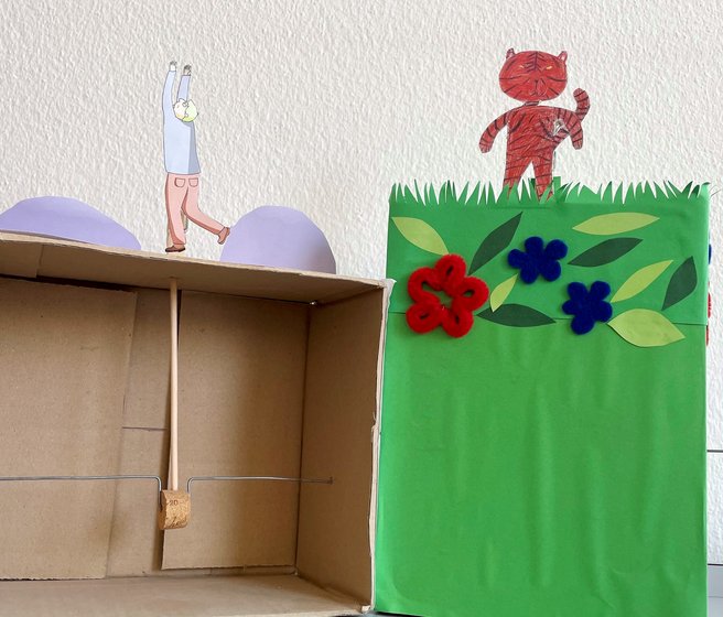 Une boite en carton, un pic en bois, un bouchon de liège, un morceau de fil de fer et un personnage en papier assemblés en un théâtre à manivelle