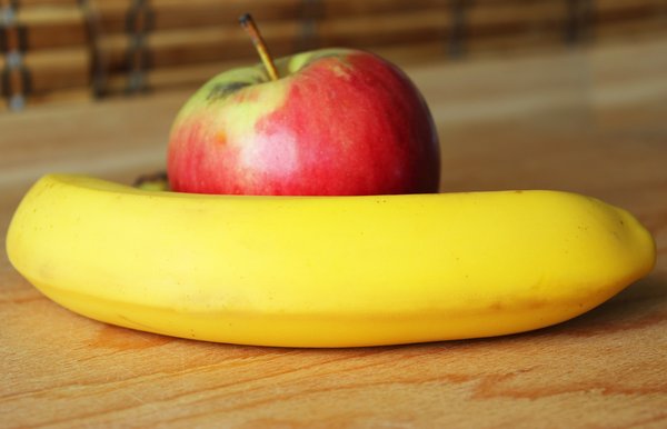 Apfel und Banane auf Holztisch