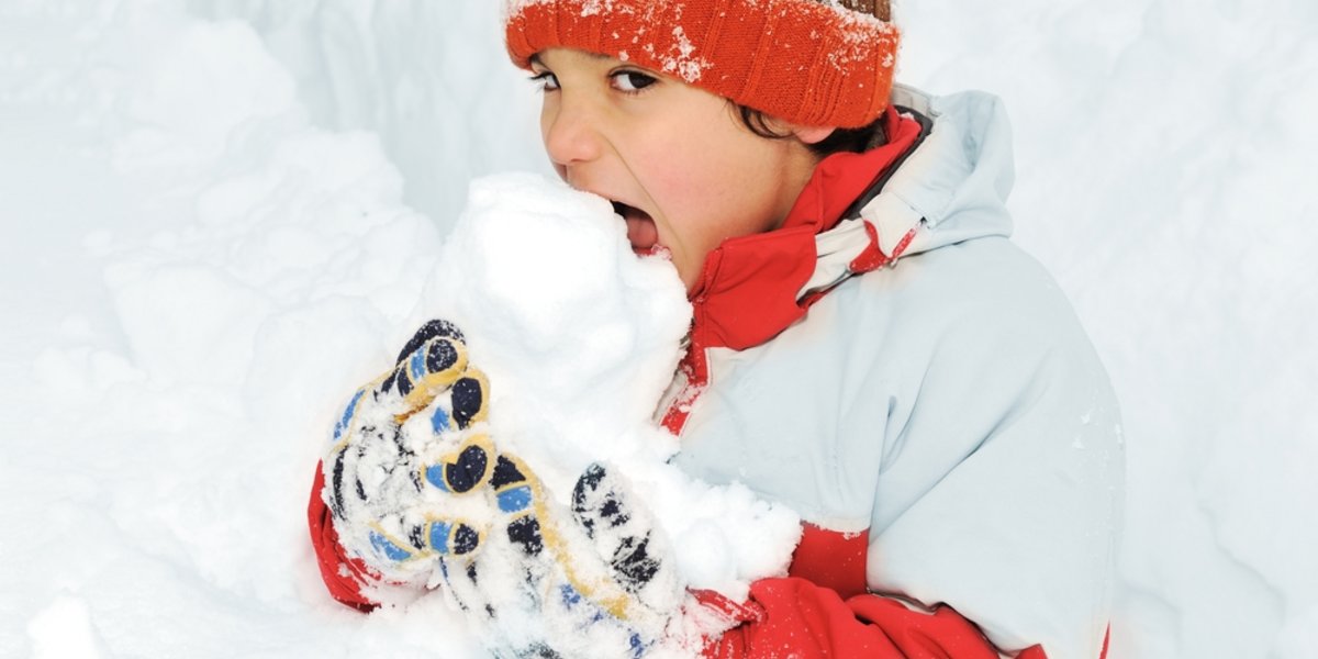 Ein Junge isst Schnee.