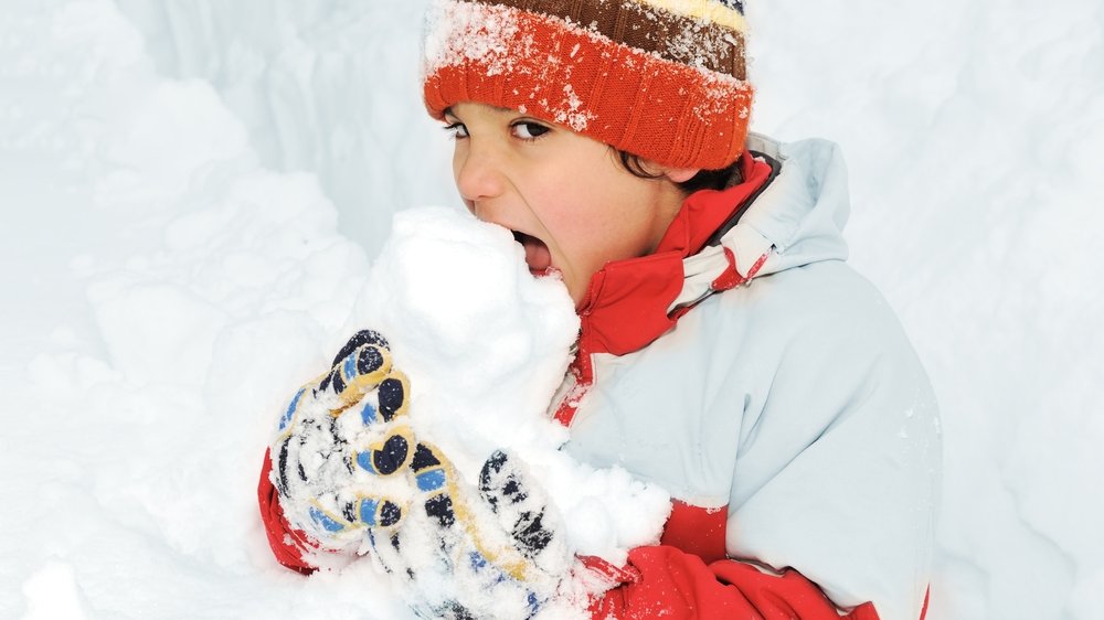 Ein Junge isst Schnee.