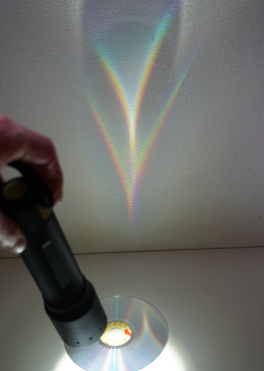 CD, mit Taschenlampe angeleuchtet, farbige Muster an der Wand