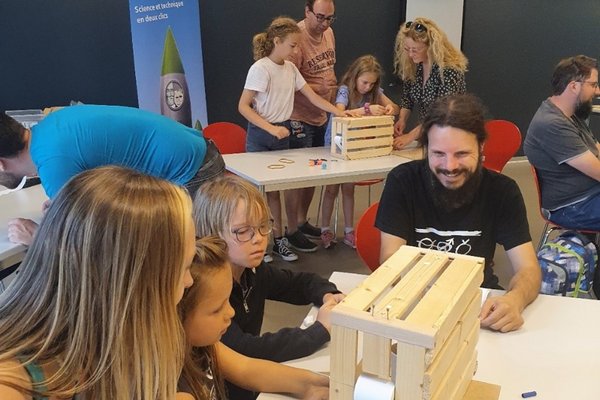 Kinder und Erwachsene beim Experimentieren mit einer Holzkiste