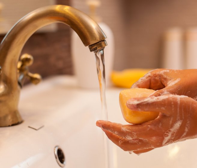 Mains avec du savon sous un jet d'eau courante