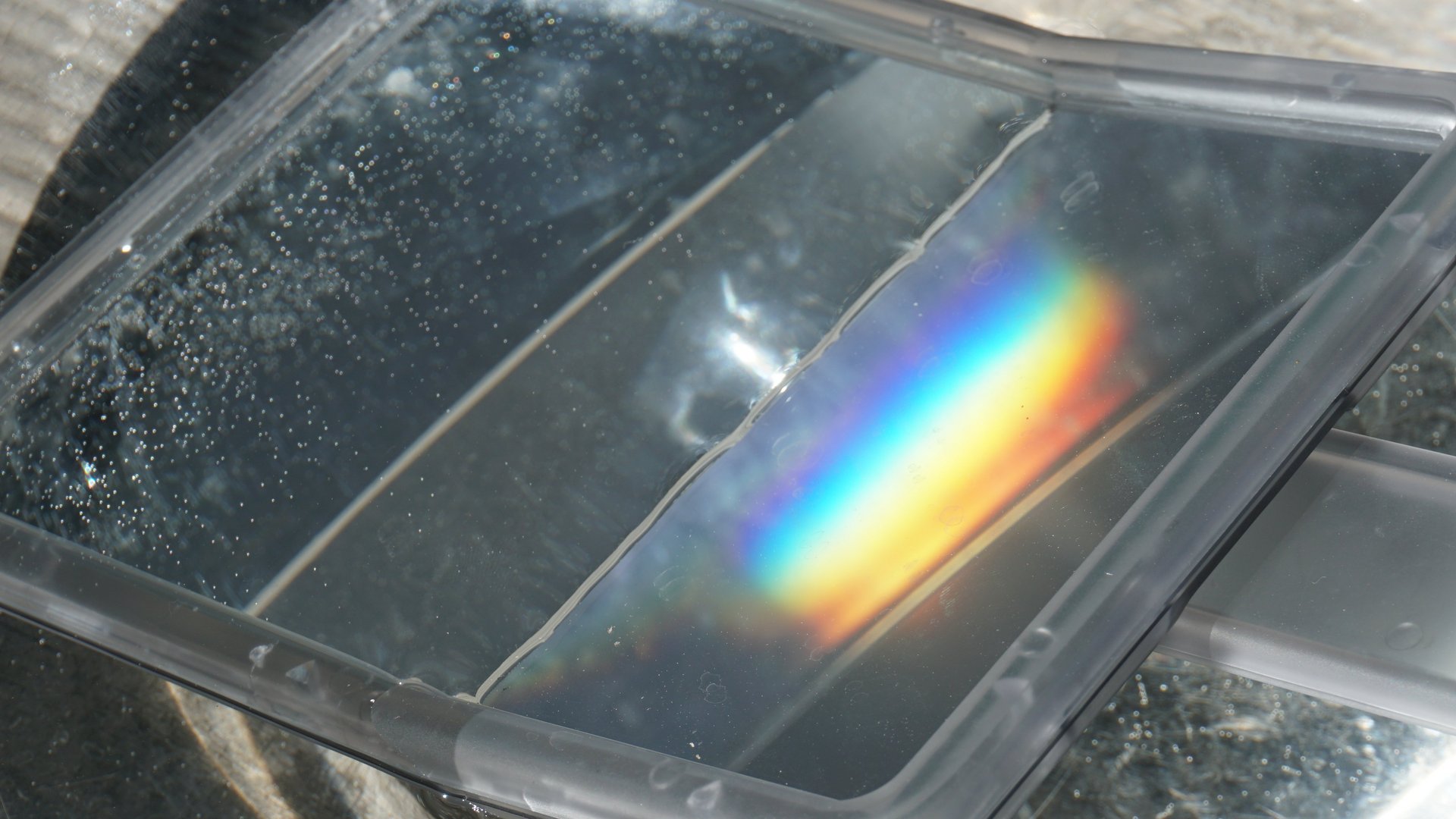 Regenbogenfarben auf einem Handspiegel in einem Wasserbecken