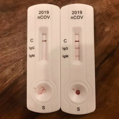 Zwei weisse Testkartuschen für Immunoassay nebeneinander; bei einer ist nur die Test-Bande sichtbar, bei der anderen erscheinen drei Banden.