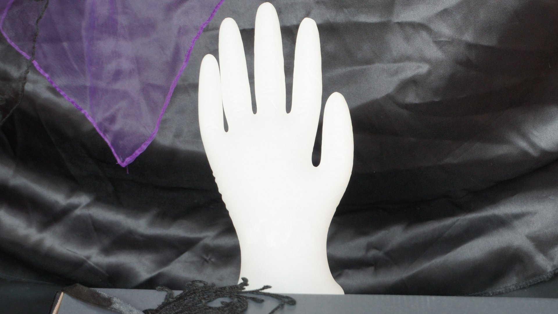 Una mano fantasma? Guanto di gomma bianco gonfiato su sfondo di raso nero