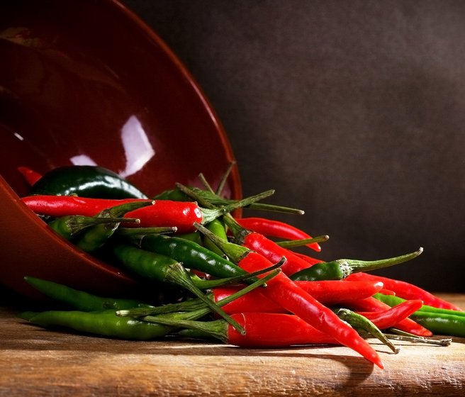 Piments rouges et verts dans un bol renversé sur la table
