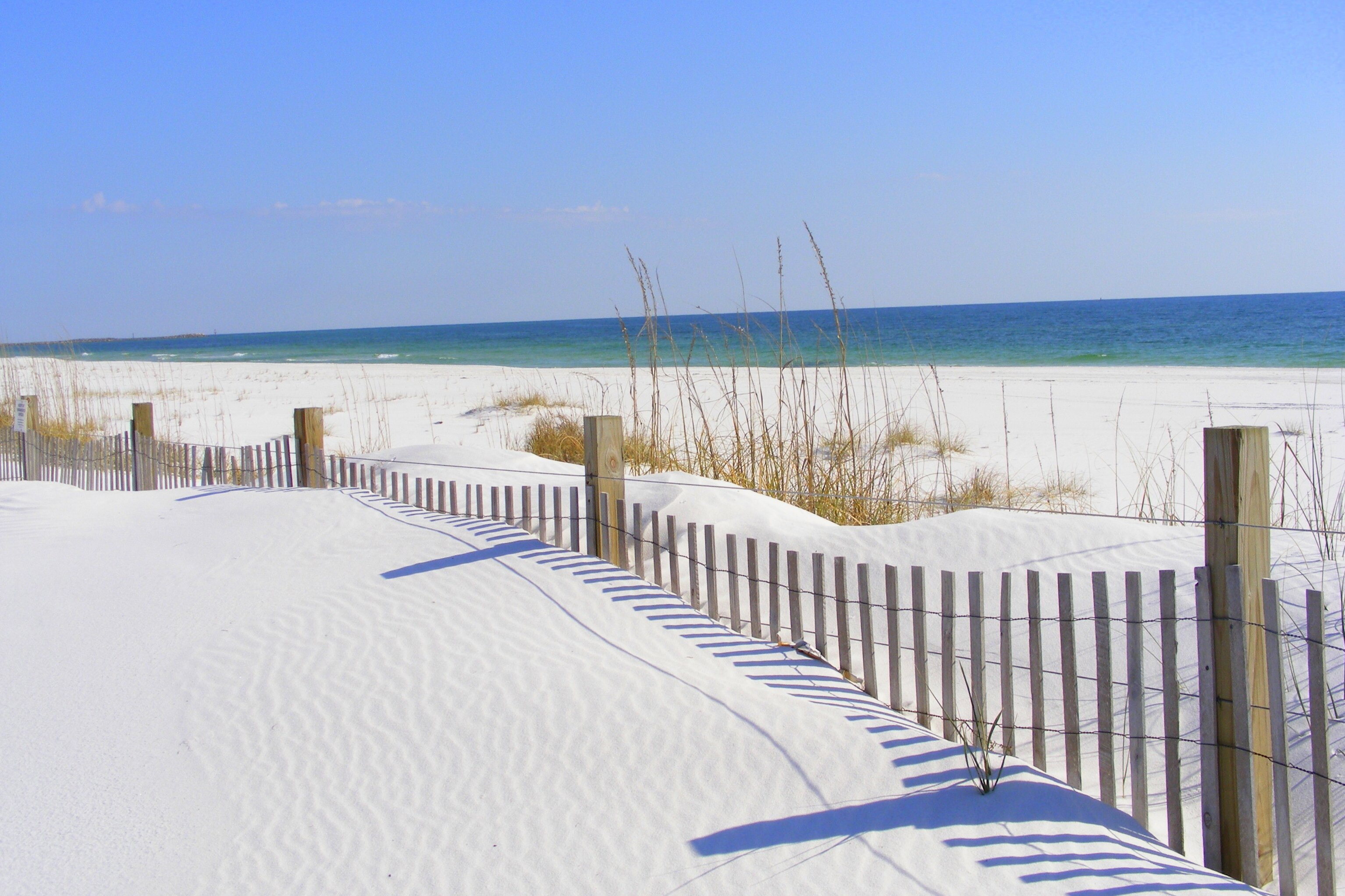 Weisser Strand mit Dünengras und Zaun