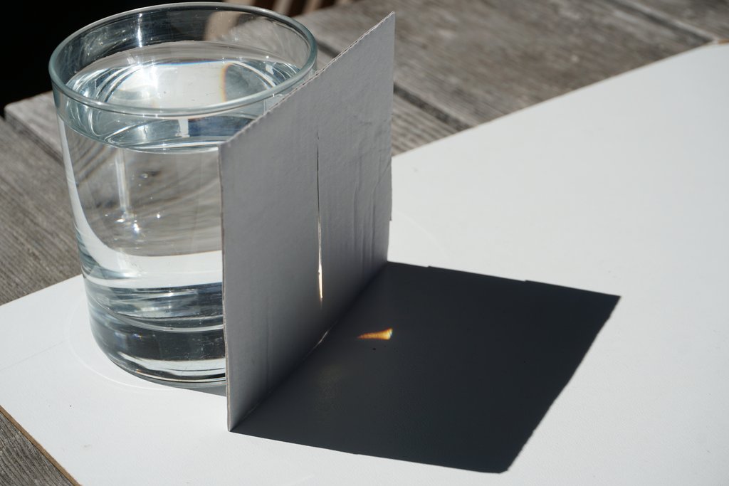 Wasserglas mit Kartonblende auf Tisch