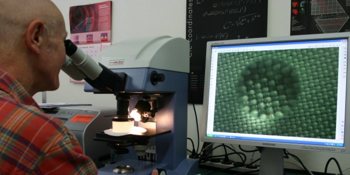 Ein Forscher kontrolliert unter dem Mikroskop einen behandelten Stoff