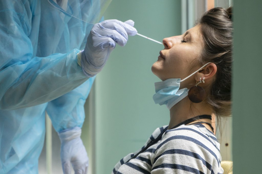 Person mit Gummihandschuhen entnimmt einer Patientin einen Nasen-Rachenabstrich
