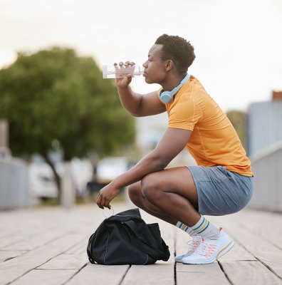 Junger Mann in Sportkleidern mit Trinkflasche