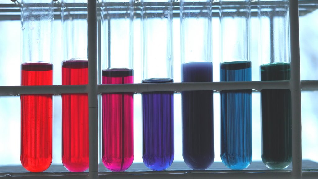 Sieben Reagenzgläser mit unterschiedlich gefärbten Flüssigkeiten