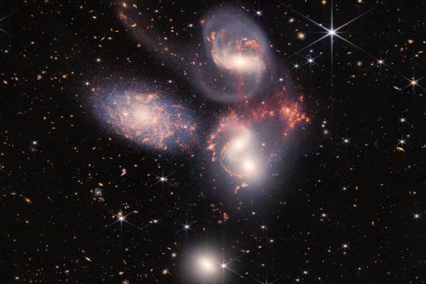 Fünf Galaxien, sichtbar als verwaschene helle Flecken auf schwarzem Hintergrund mit Sternen
