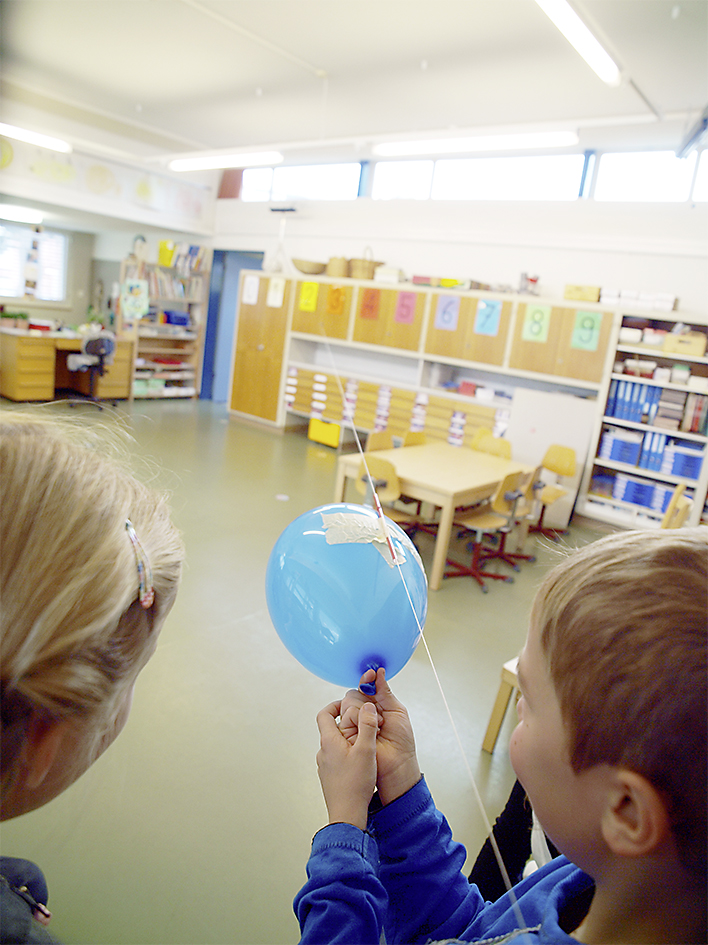 En lâchant le ballon, il va glisser le long de la ficelle grâce à la paille