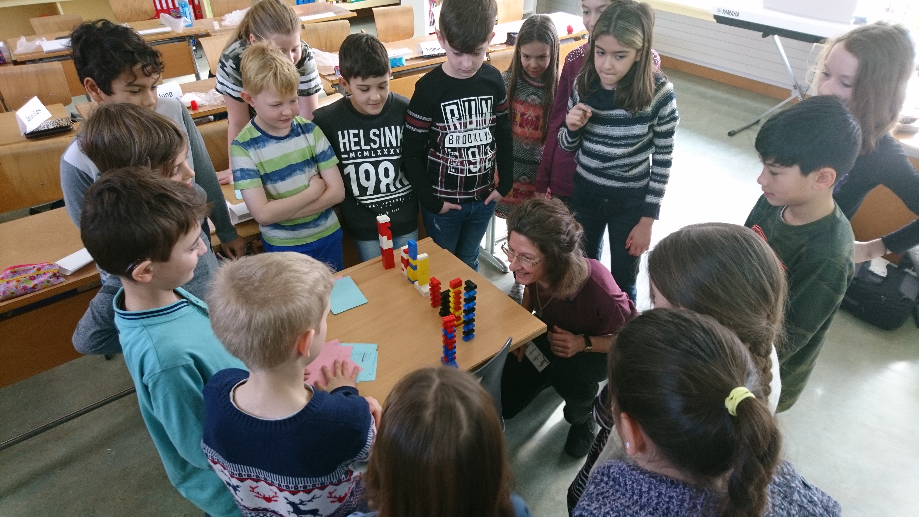 Gruppe von Schulkindern mit Instruktorin um einen Tisch beim Experimentieren