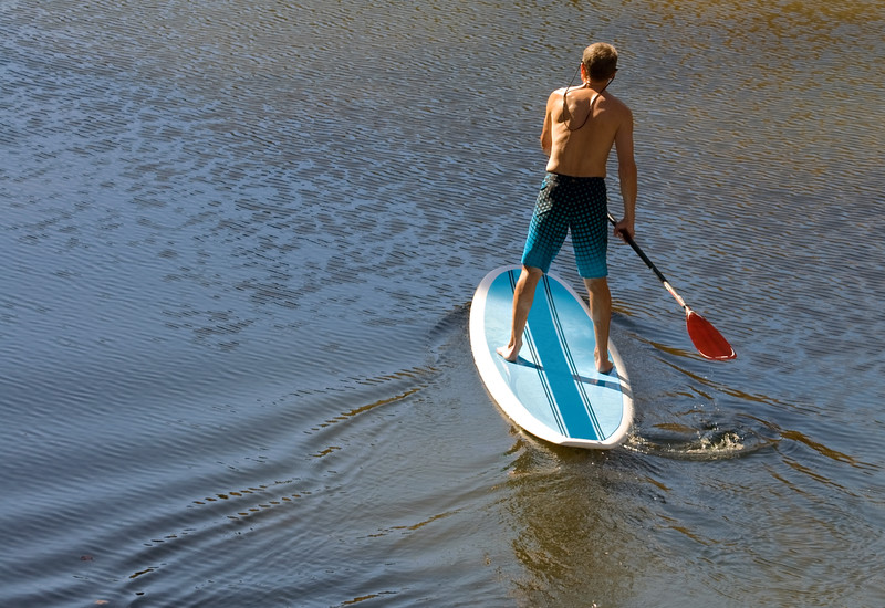 Un homme debout sur un stand up paddle