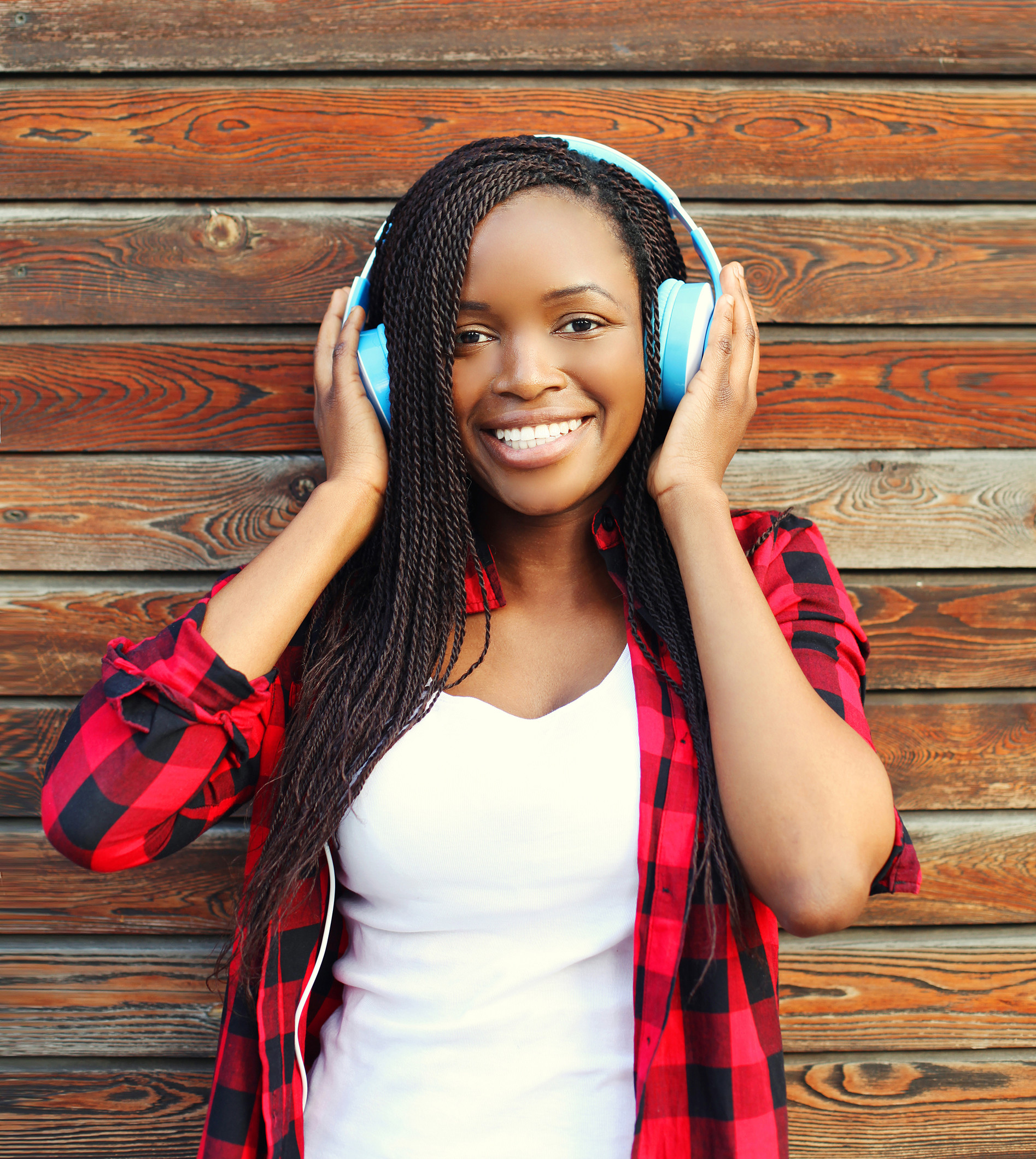 Fröhlich lächelnde junge Frau, die Musik hört.