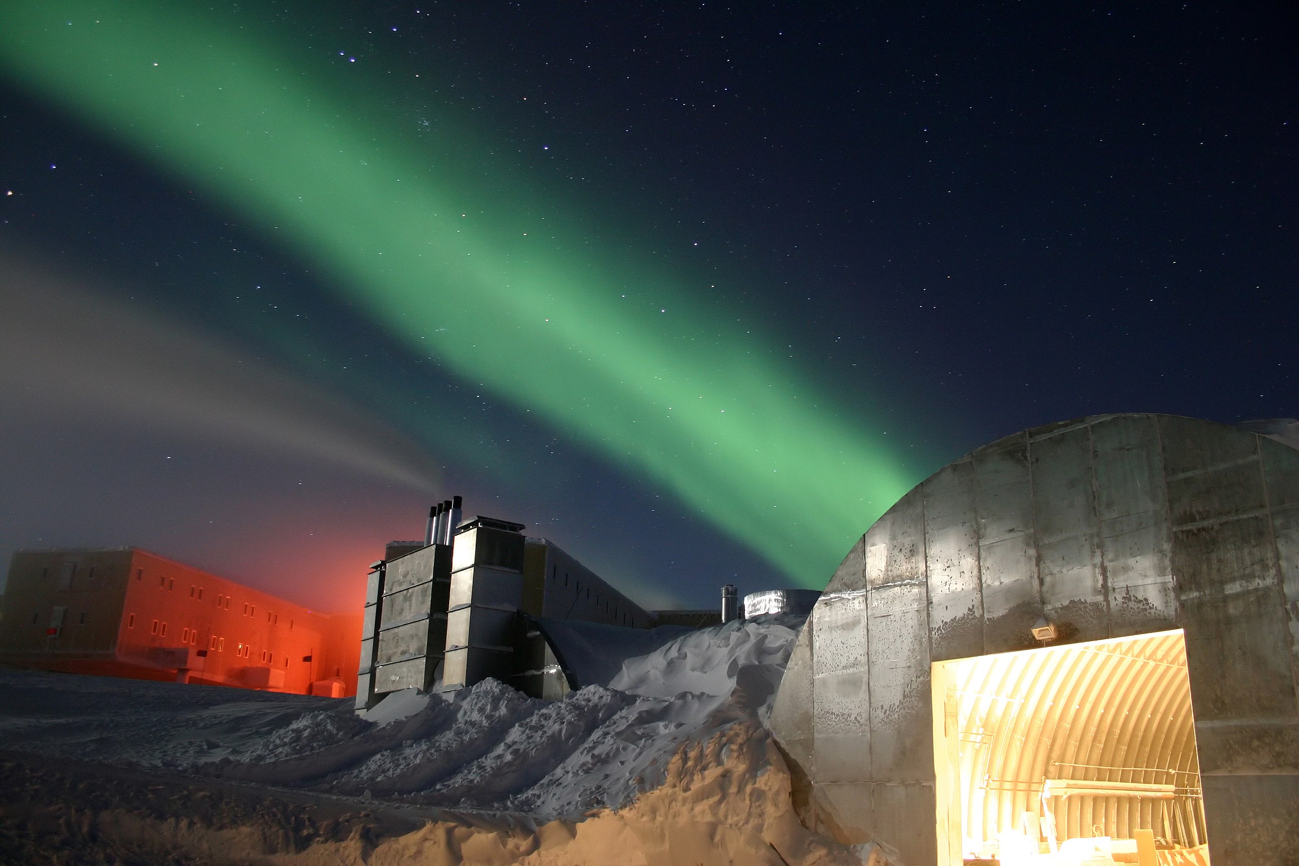 Zwei Gebäude in der Nacht unter einem grünen Polarlicht