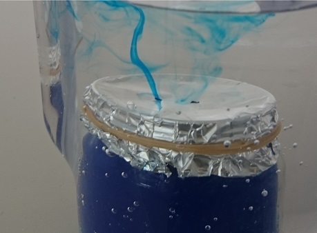 L'eau colorée monte dans l'eau froide si on perce des trous dans le papier d'aluminium